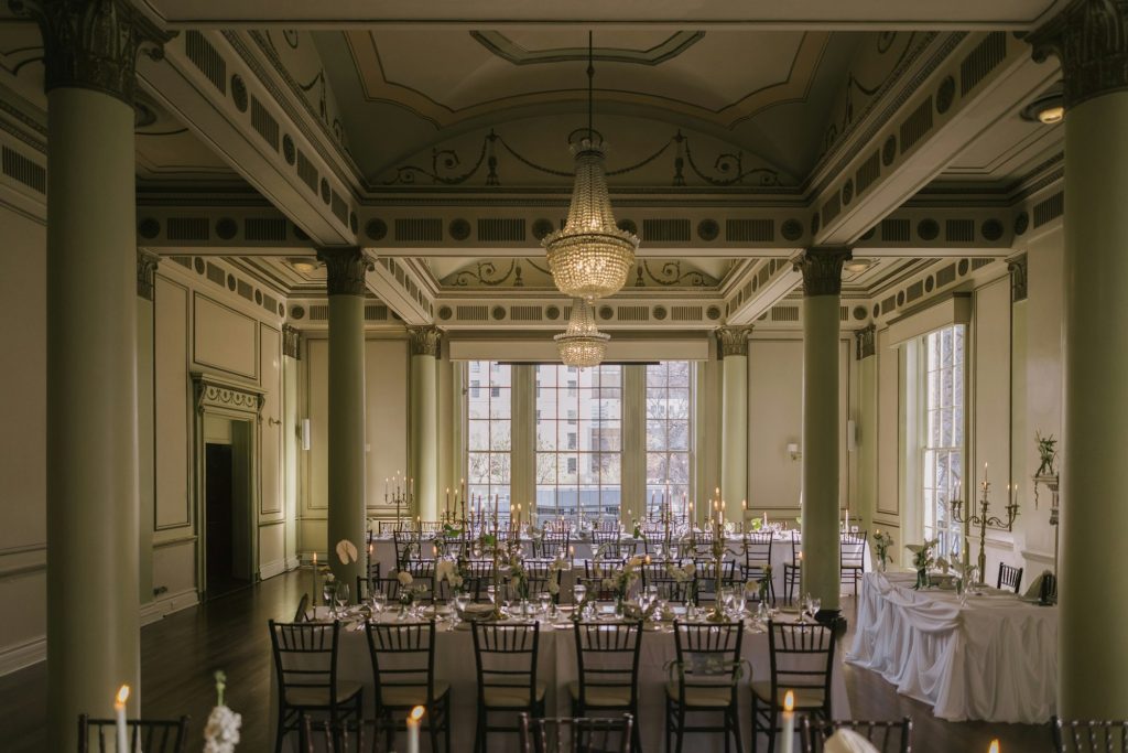 Grand ballroom with long tables, chandeliers and tall columns