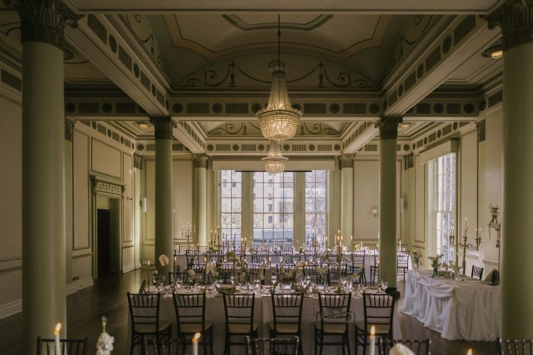 Grand ballroom with long tables, chandeliers and tall columns